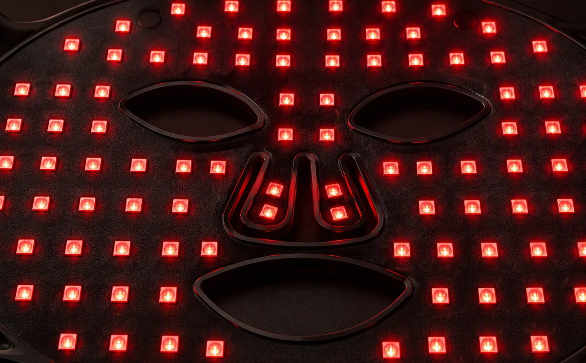 Close-up of red LED chips glowing on a black silicone LED face mask